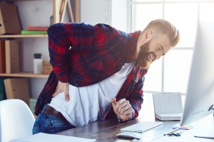 Mann-Schreibtisch-Rueckenschmerzen-envato