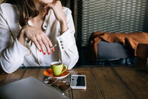 Schlechte Gewohnheiten loswerden: Eine Frau mit Handy und Zigarette