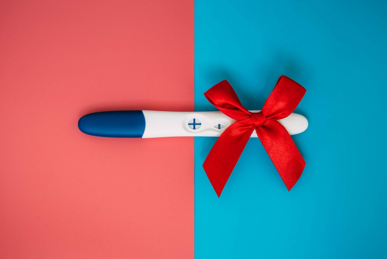 Positiver Schwangerschaftstest liegt auf einem rot-blauen-Hintergrund und kann statt einer Schwangerschaft auch auf Hodenkrebs oder andere Tumore hinweisen