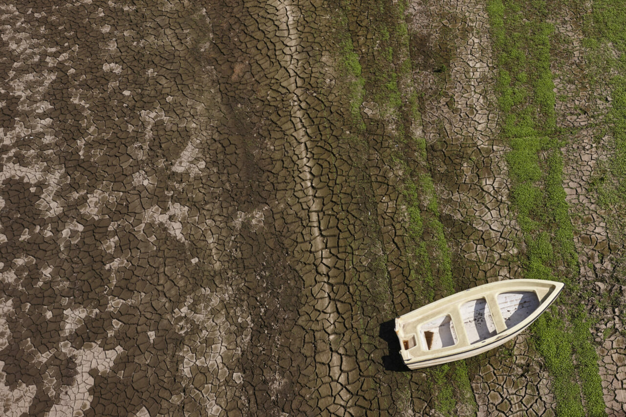 Luftaufnahme eines Bootes auf dem Grund eines ausgetrockneten Gewässers symbolisiert die Situation der Dürre in Europa
