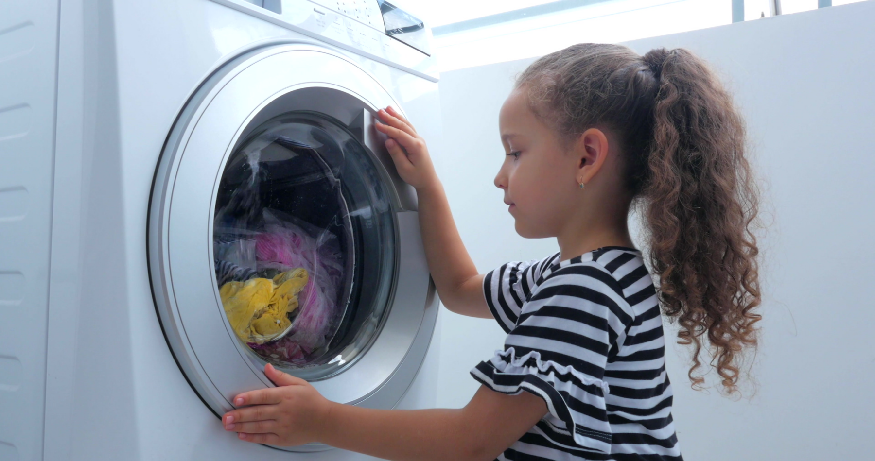 Kind schaut ins Fenster der Waschmaschine